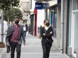 Un hombre y una mujer con mascarilla caminan por una calle de O Grove, en Galicia.