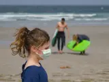 Una ni&ntilde;a paseando con mascarilla por la playa