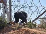 Inmigrantes colándose por la valla de Ceuta.