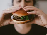 Una persona comiéndose una hamburguesa.