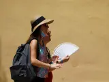 Dos chicas sin mascarilla tratan de sofocar el calor con un abanico en Córdoba.