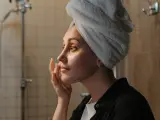 Una mujer se aplica productos cosméticos en el rostro.