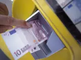 Una persona retira 10 euros de un cajero autom&aacute;tico.