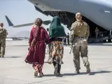Una integrante del cuerpo de la Marina estadounidense acompa&ntilde;a a dos ni&ntilde;as para evacuarlas en el aeropuerto de Kabul.