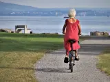 Una sexagenaria pasea en bicicleta por un parque.