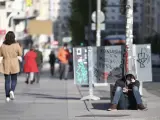 Un chico consulta el móvil sentado en la acera de la Gran Vía de Madrid.
