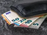 Varios billetes sobresalen de una cartera.