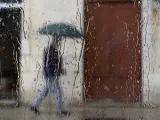 Un hombre camina bajo la lluvia en Santander.