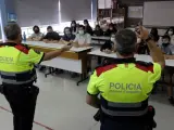 Dos agentes de los Mossos d'Esquadra impartiendo una charla en una escuela.