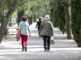 Un anciano y una mujer pasean en un parque en Madrid.