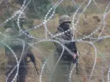 Dos militares polacos vigilan la frontera tras el alambre de espino.