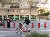 Un usuario del Bicing pedalea frente a una estación sin bicis.