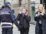 Un agente de Policía vigila que se cumpla la obligación de llevar mascarilla en exteriores en Milán (italia).