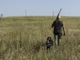 Un cazador camina junto a un perro.