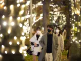 Viandantes con mascarillas por la pandemia de covid-19, en una calle de Tokio, Japón, iluminada con luces de Navidad.