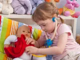 Una niña jugando a ser pediatra de su muñeco.