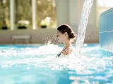 Mujer disfruta de la corriente de la cascada en la piscina del balneario.