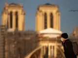 Una persona con mascarilla camina junto a la catedral de Notre Dame en París (Francia).