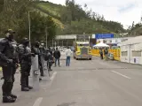 Policías vigilan mientras camiones cruzan la frontera entre Ecuador y Colombia tras su reapertura después de su cierre por la pandemia del coronavirus, en Tulcán (Ecuador).