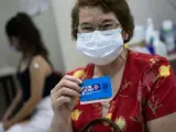 Una mujer posa con su carné de vacunación tras haber recibido la cuarta dosis.