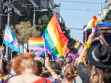 Personas levantando y sosteniendo la bandera del arco iris, símbolo de la comunidad LGBTQ+