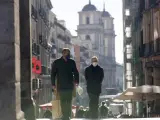 Dos personas caminan bajo uno de los arcos de acceso a la Plaza Mayor de Madrid.