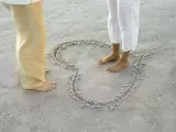 Dos personas, junto a un corazón dibujado en arena de playa, en una imagen de archivo.