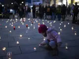 Una ni&ntilde;a coloca una vela en un acto contra la guerra en Ucrania celebrado en Suiza.