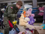 Un soldado polaco regala un peluche a una niña refugiada ucraniana.