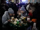 Dos mujeres y una ni&ntilde;a comen en la estaci&oacute;n de tren de Lviv