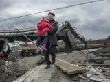 Un hombre lleva en brazos a una niña entre los escombros de un puente, tras un bombardeo ruso en Irpin, cerca de Kiev (Ucrania).