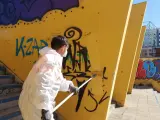Un trabajador de Lipasam retira una pintada en la vía pública.