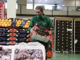 Un trabajador de Mercabarna coloca producto en una parada de frutas y verduras