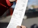 Un cliente muestra el ticket de su repostaje en el que se ha aplicado un 20% de descuento.