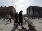 Varias personas caminan junto a edificios destruidos por los bombardeos en Mariúpol, Ucrania, el 10 de abril de 2022.
