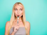 Close-up portrait of her she nice attractive lovely sweet feminine girlish, straight-haired girl holding in hand kitchen ware licking fork isolated on bright vivid shine green blue turquoise background