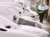 Un hombre se protege a duras penas de la nieve por una calle de Ávila.
