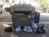 Un contenedor de Barcelona con basura por los lados.