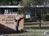 Un agente de Policía deposita flores en la entrada de la escuela de primaria Robb, en Uvalde (Texas, EE UU), donde un joven mató a 19 niños y dos profesoras.