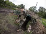 El soldado ucraniano 'Den' sale de una trinchera en un bosque de Ucrania.