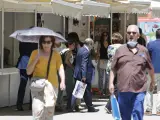 Varias personas caminan bajo el sol en la Feria del Libro de Madrid, este jueves.