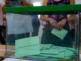 Numerosas papeletas se amontonan en el interior de una urna en un colegio electoral de Sevilla.