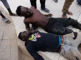 Dos migrantes descansan tras saltar la valla de Melilla.