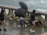 Varias personas con paraguas caminan por el Paseo Marítimo de La Coruña, Galicia.
