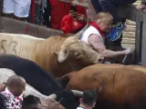 Un mozo es alcanzado por uno de los toros de la ganadería gaditana Núñez del Cuvillo a su llegada a la curva de la calle Estafeta, durante el primer encierro de los Sanfermines 2022.