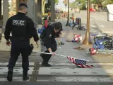 Un policía recoge una bandera abandonada tras el tiroteo en Highland Park, Illinois (EE UU), donde un joven disparó contra la multitud durante el desfile del Día de la Independencia.