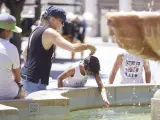 Una madre le echa agua a su hijo por la cabeza para sofocar el calor en Sevilla este sábado.