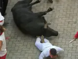 Un mozo caído en el suelo tras ser embestido por uno de los toros de Jandilla, en el sexto encierro de los Sanfermines 2022.