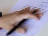 Una mujer con un bolígrafo señala una escritura de compraventa de una hipoteca.