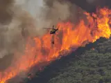 Un helicóptero trabaja en las tareas de extinción del incendio declarado en el paraje El Higuerón de Mijas (Málaga).